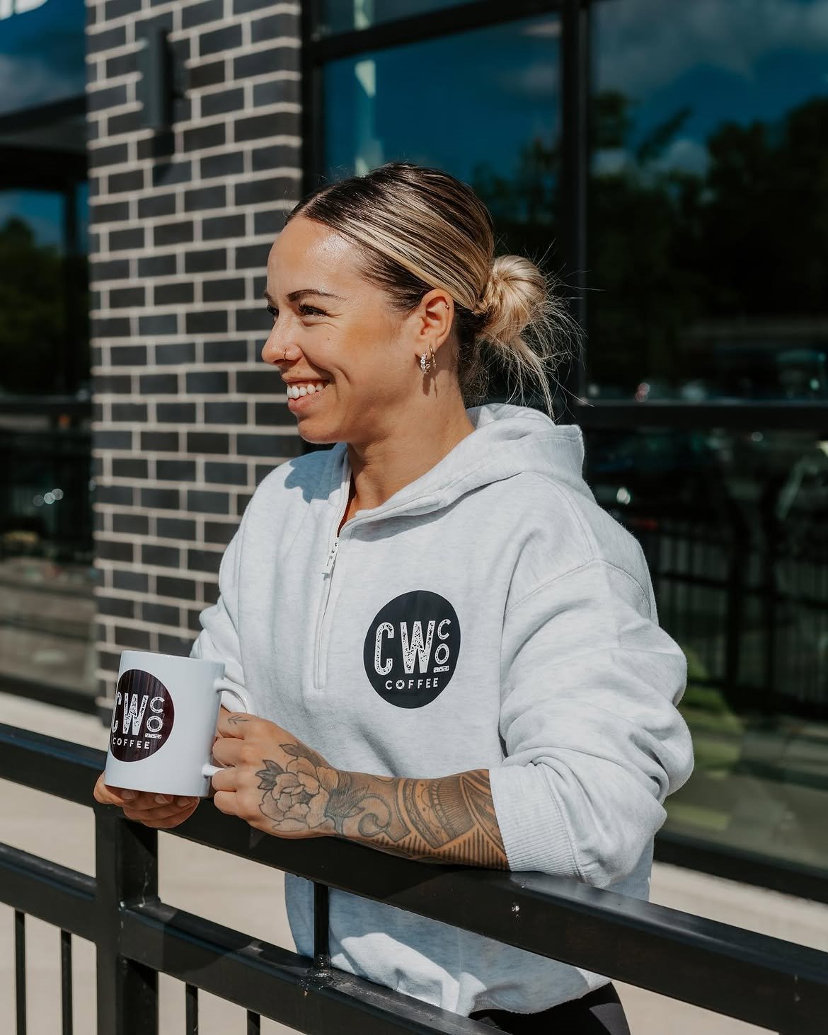Commonwealth Coffee team member holding a branded mug outside the café